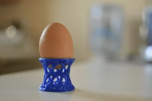 Blue 3D printed egg holder with an egg