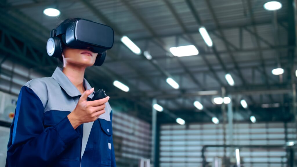 Industrietechniker der ein VR-Headset trägt und einen Controller in einer Fabrikumgebung verwendet um ein Fernwartungstraining zu demonstrieren.